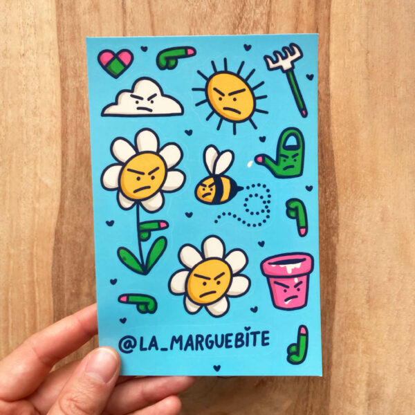 Main tenant une planche de stickers Marguebite sur fond en bois – illustrations rigolotes de fleurs, abeille, soleil et pot de fleur
